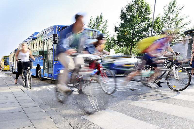 Eine Gruppe Radfahrende in der Stadt fährt zusammen mit einem Linienbus los